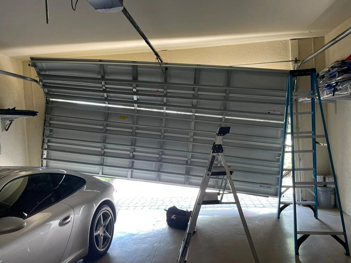 Raised garage door with a ladder and a parked car inside