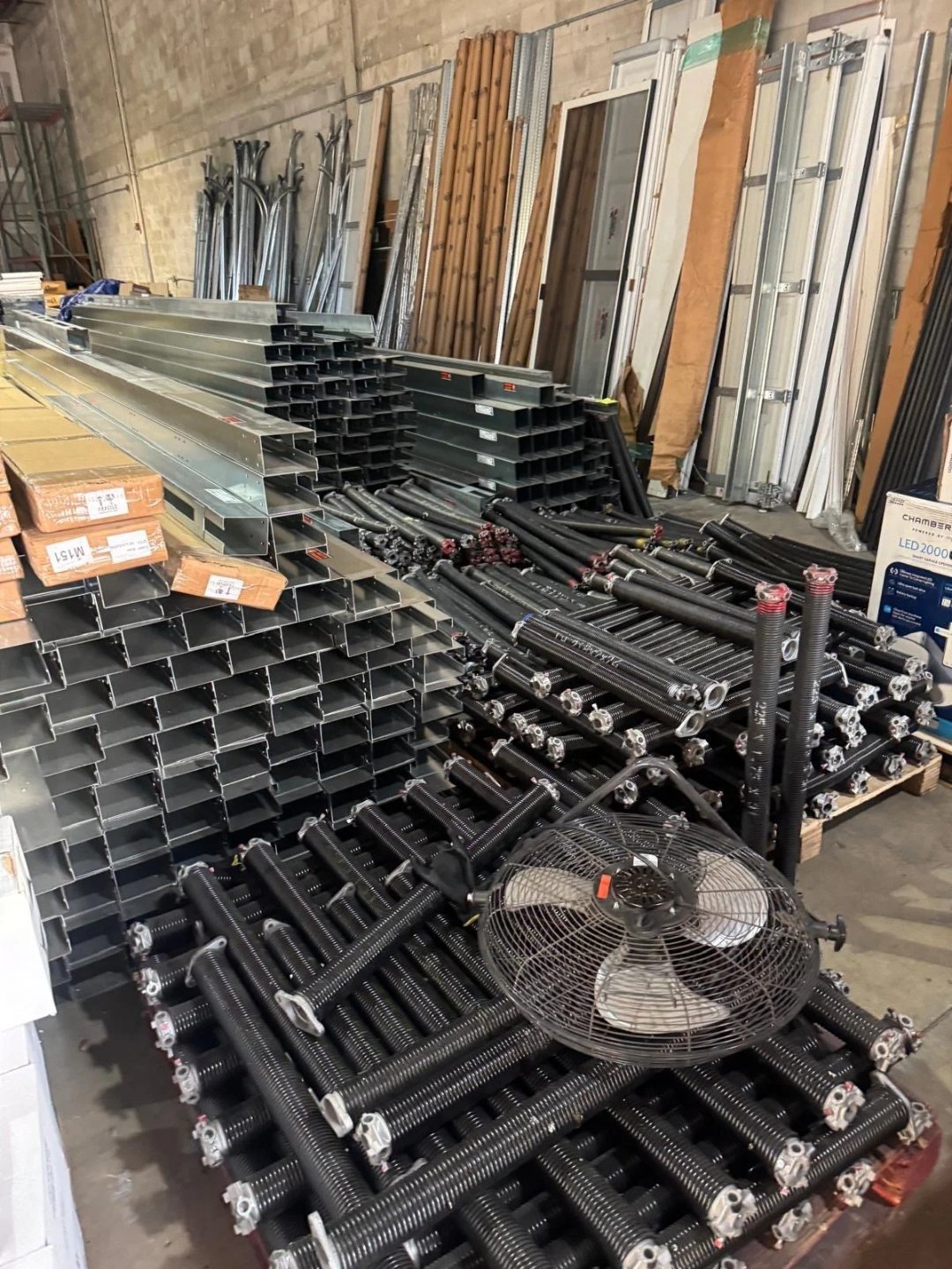 Stacked garage door track sections and hardware ready to install