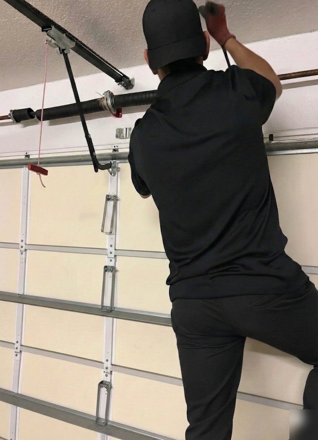 Technician reaching up to the spring hardware above a white door