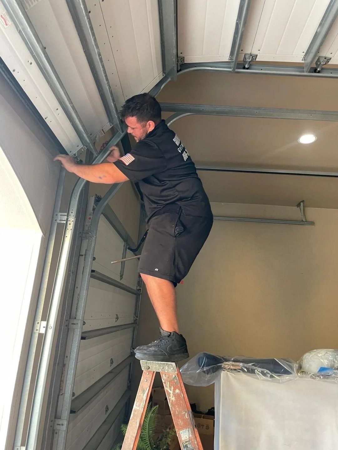 Technician climbing a ladder next to the vertical door track